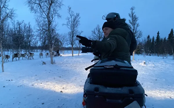 On a snowmobile, pointing out reindeer in the snow