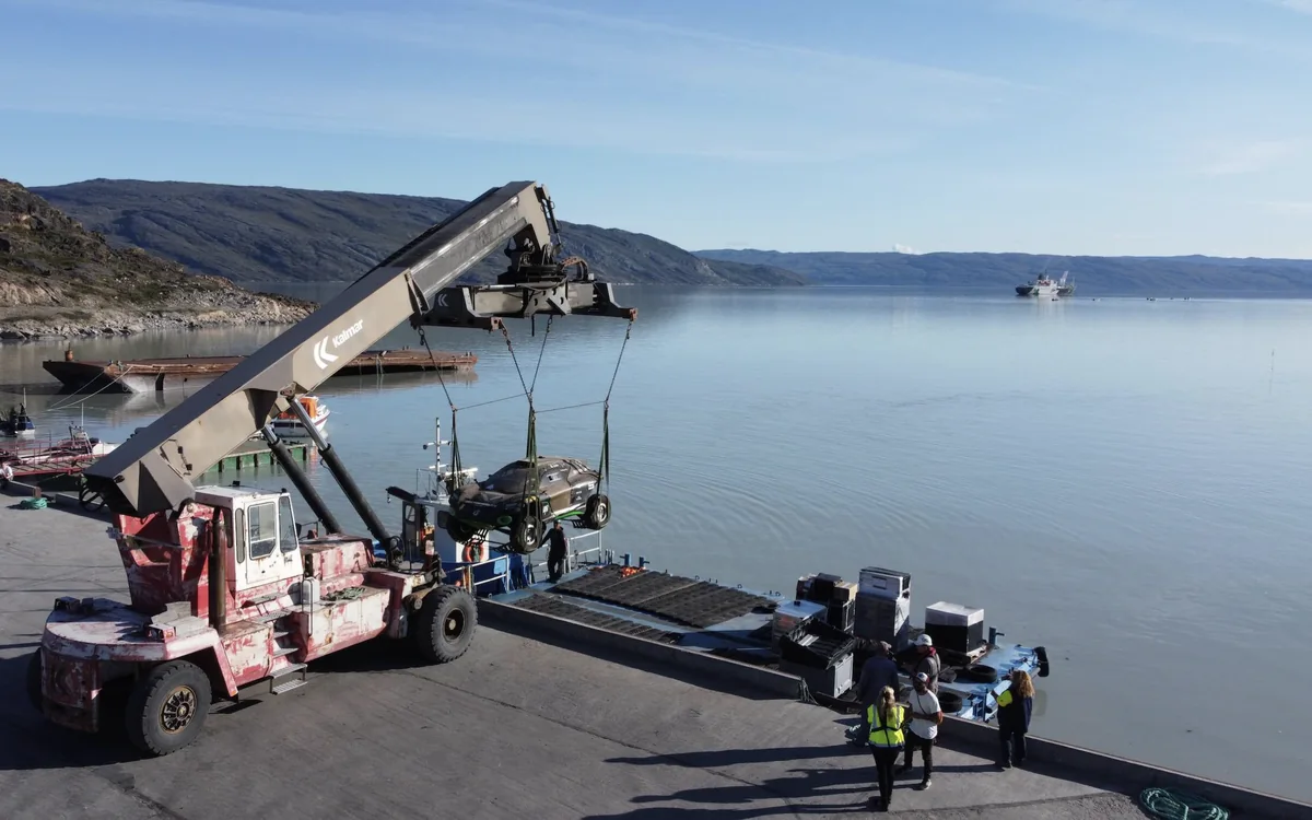 A race car lifted off a barge at the quay in Kangerlussuaq