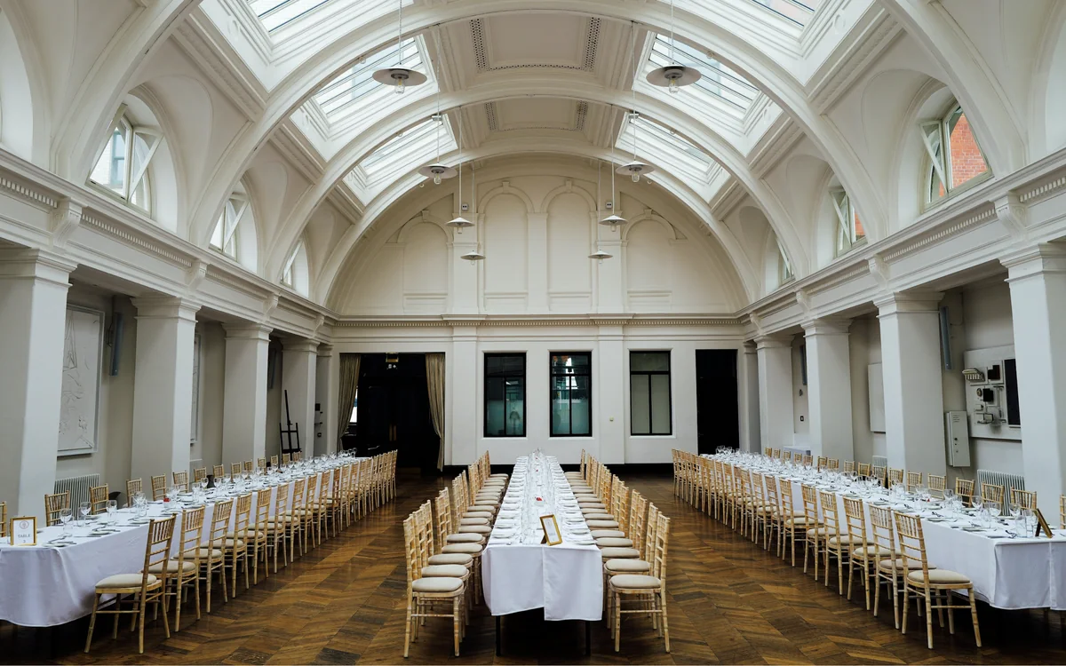 Long banquet tables under a skylit vaulted hall