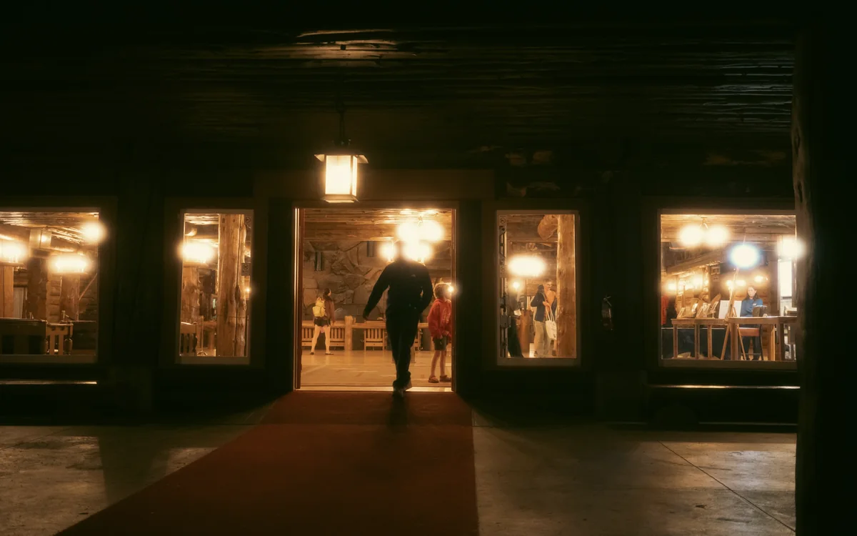 A guest walking into a warmly lit lodge at night