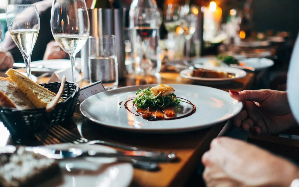 Champagne, a first course and candles on a restaurant table laid for dinner