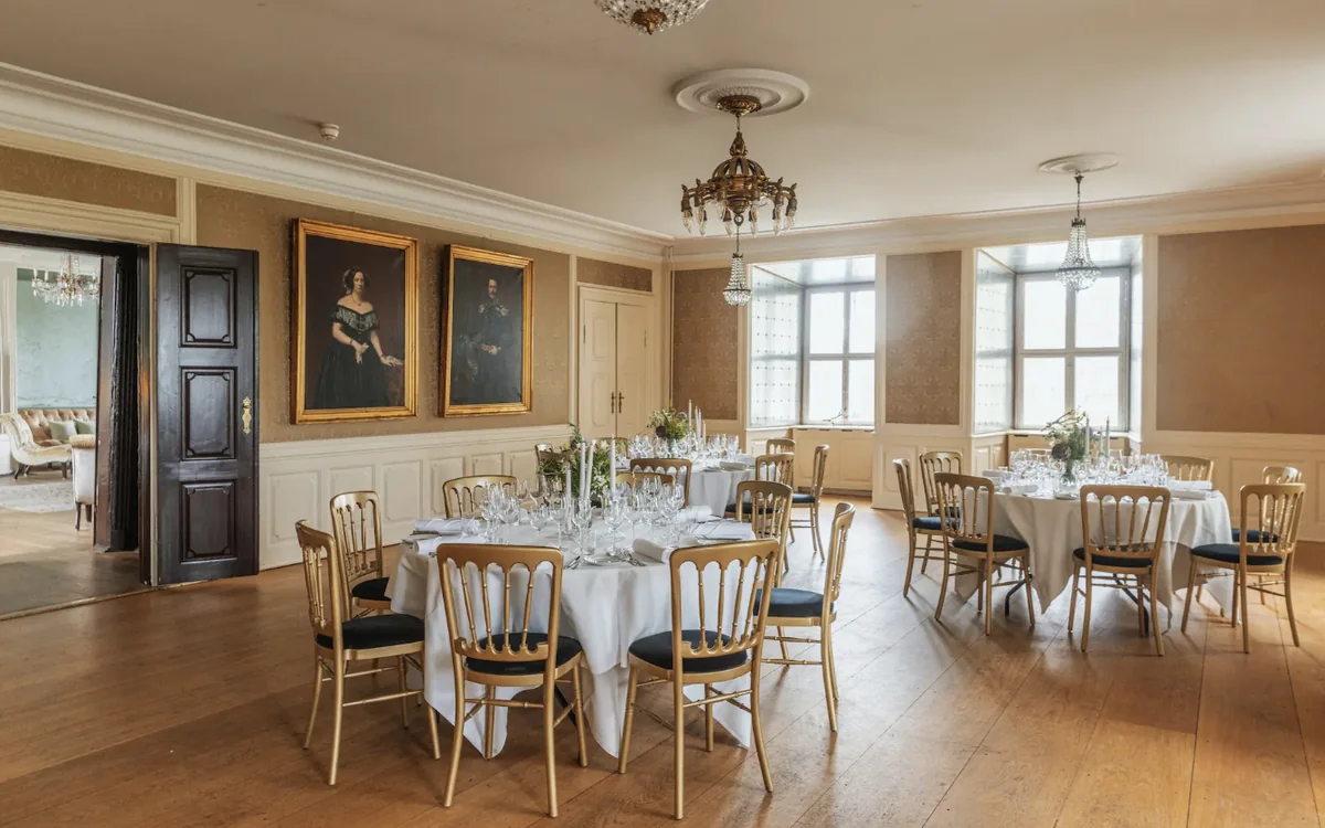 Dragsholm Slot: A hall with chandeliers and portraits, laid with round tables
