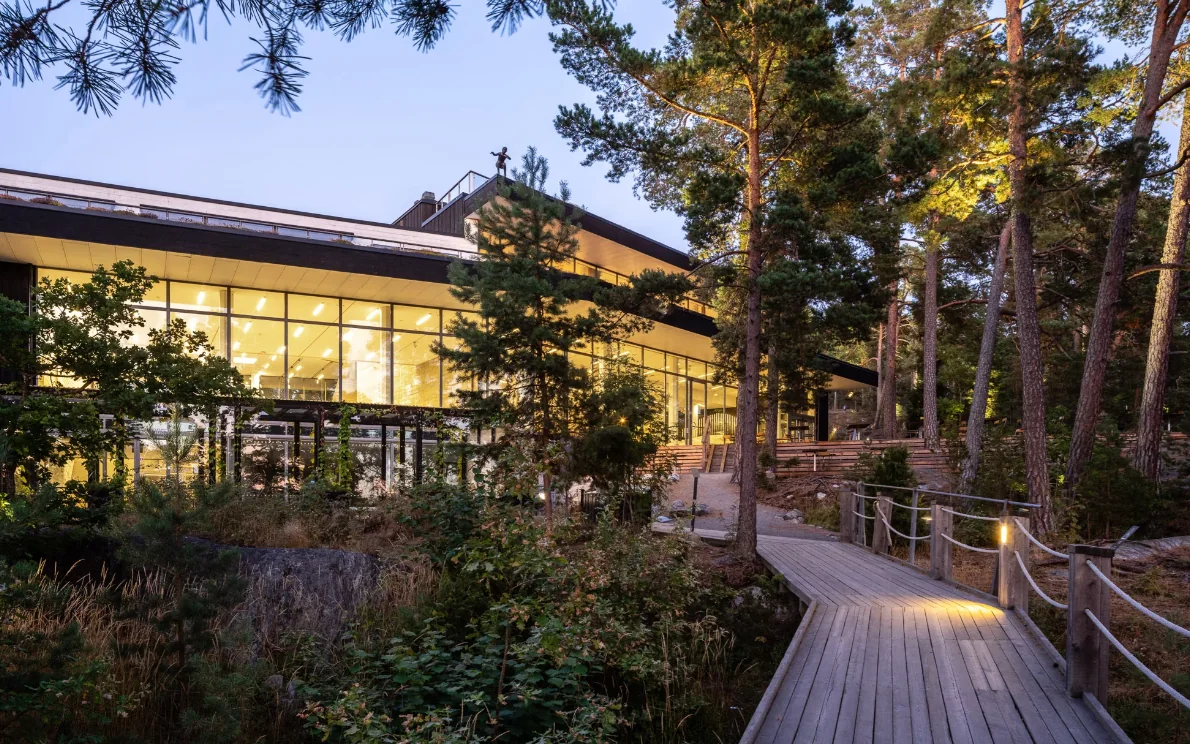 Artipelag: The building lit at dusk among the pines, with a boardwalk