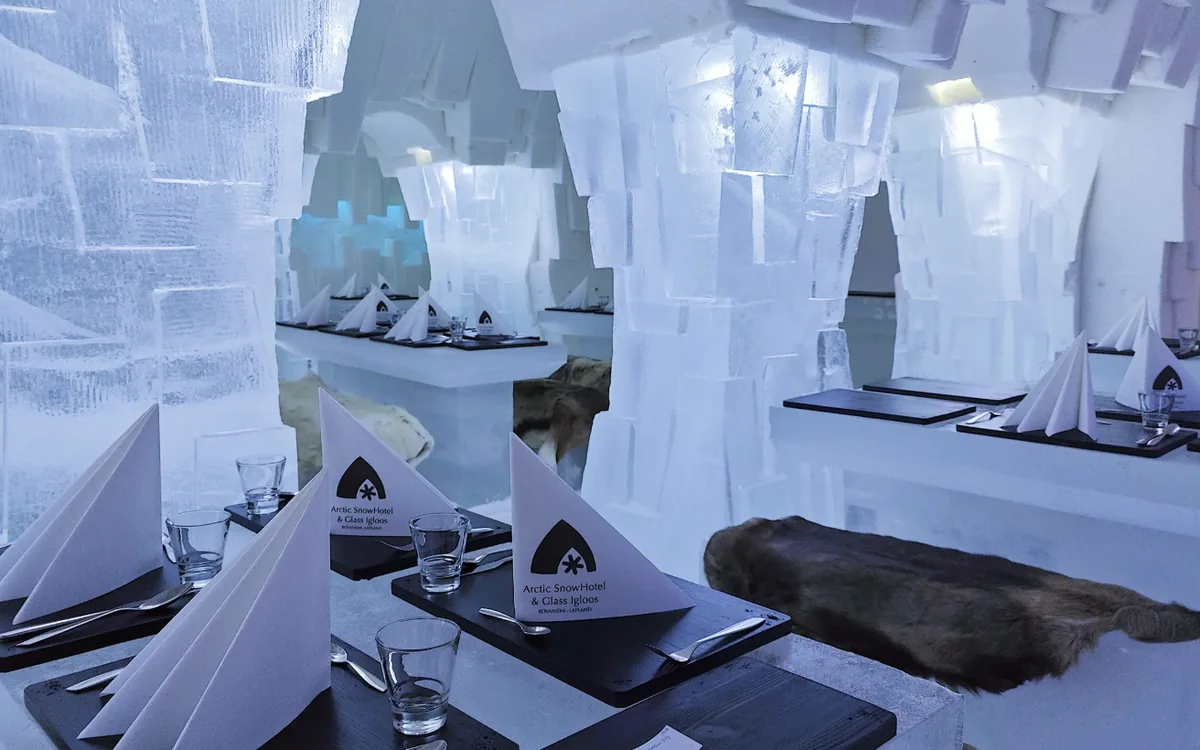 Arctic SnowHotel: The ice restaurant laid for dinner, reindeer hides on the benches
